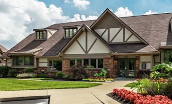 Autumn woods clubhouse with a brown roof and white walls with a green lawn in front